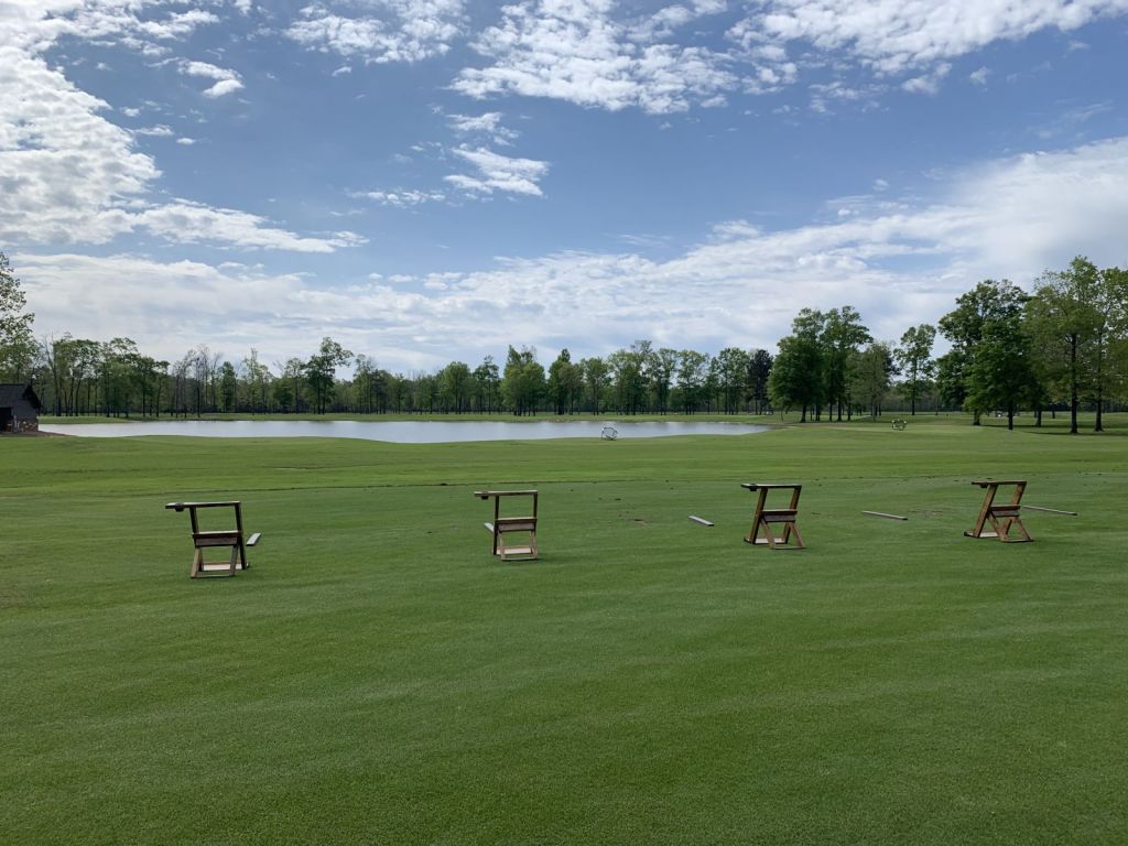 Scenic Aqua Driving Range showing grass tee area with bag stands at The Refuge Golf Course